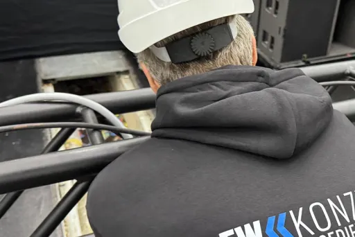 Mann mit Helm und CREWKONZEPT-Pullover arbeitet auf einer Bühne.