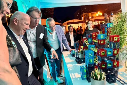 Der Regierende Bürgermeister von Berlin betrachtet bunte Modelle auf einem Tisch beim Hoffest