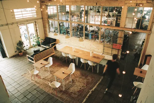 Heller, moderner Coworking-Space mit Holztischen, Stühlen und gemütlicher Beleuchtung.
