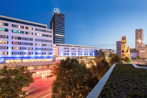 Moderne Stadtansicht bei Dämmerung mit beleuchteten Gebäuden und Hochhäusern.