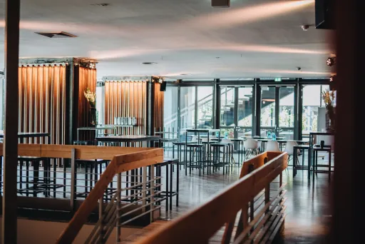 Modernes, lichtdurchflutetes Café mit Holzmöbeln und großen Fenstern.