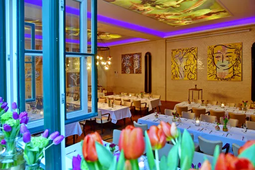 Elegant gedeckter Speisesaal mit Tulpen im Vordergrund und bunter Beleuchtung