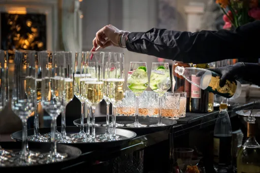 Barkeeper füllt Sekt in Gläser an einer festlich gedeckten Bar.