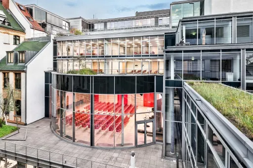 Modernes Gebäude mit Glasfassade und rotem Bestuhlungsraum im Innenhof