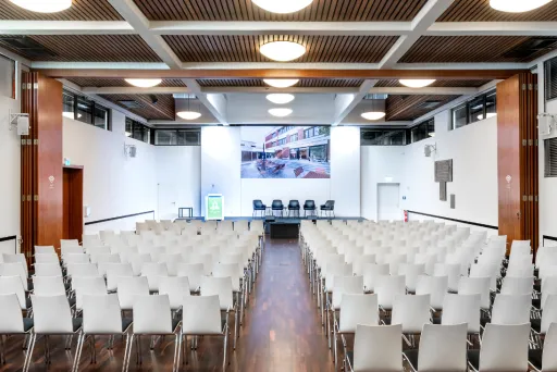 Leerer Konferenzraum mit weißen Stühlen und Podium vorne