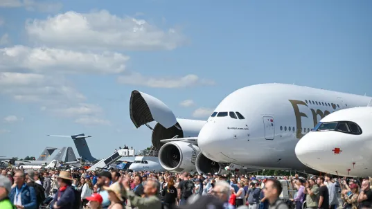 Menschenmenge vor großen Passagierflugzeugen bei einer Flugschau unter blauem Himmel.