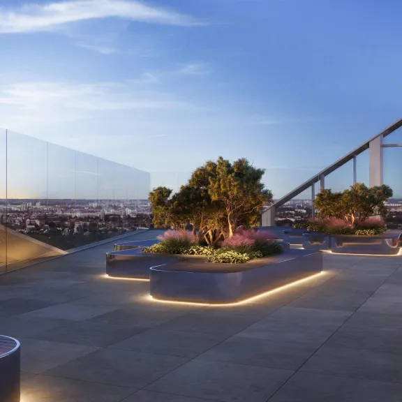 Dachterrasse mit Pflanzenbeeten, moderner Beleuchtung und Blick auf die Stadt bei Sonnenuntergang.