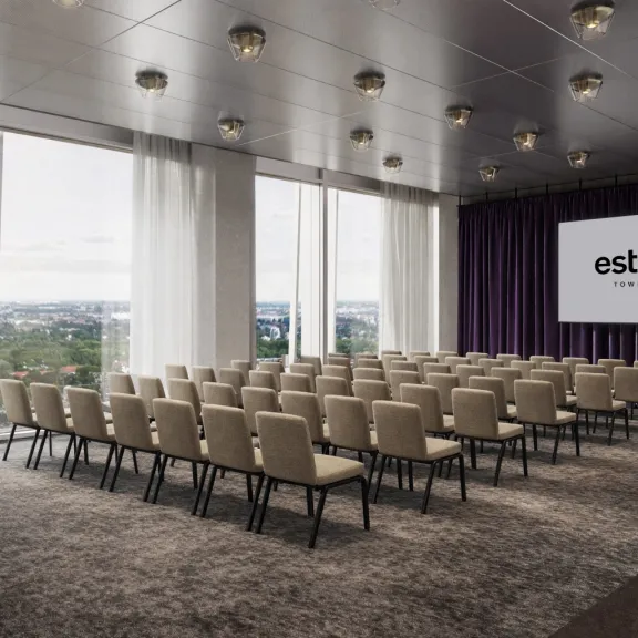 Konferenzraum mit Stuhlreihen, großer Fensterfront und Projektion auf Leinwand