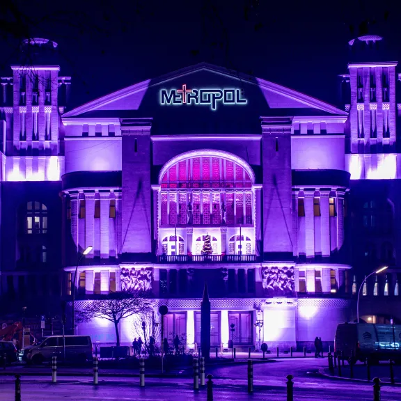 Beleuchtetes Theatergebäude bei Nacht in violetten und blauen Farbtönen
