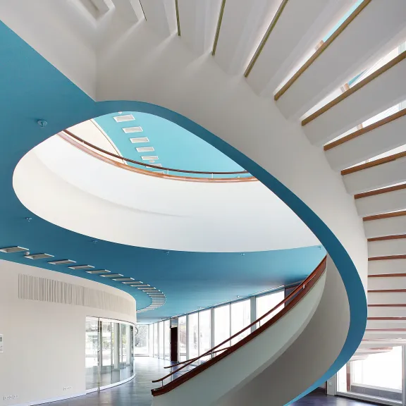 Moderne Wendeltreppe mit blauem Deckenelement und viel Tageslicht
