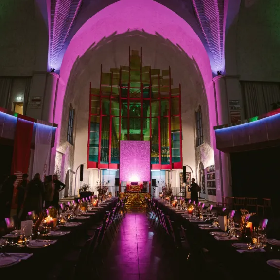 Festlich gedeckte Tische in einer bunt beleuchteten Kirche mit hoher Decke.