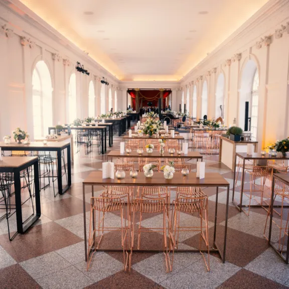 Eleganter, heller Saal mit festlich gedeckten Tischen und Blumenarrangements.