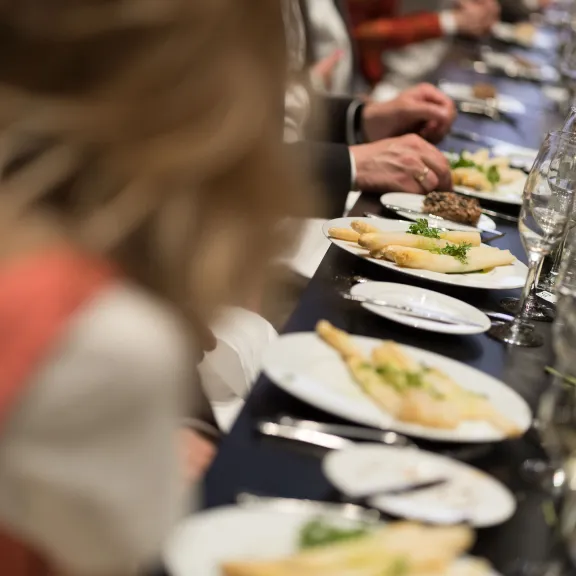 Menschen essen zusammen an einem festlich gedeckten Tisch mit Weingläsern und Tellern.