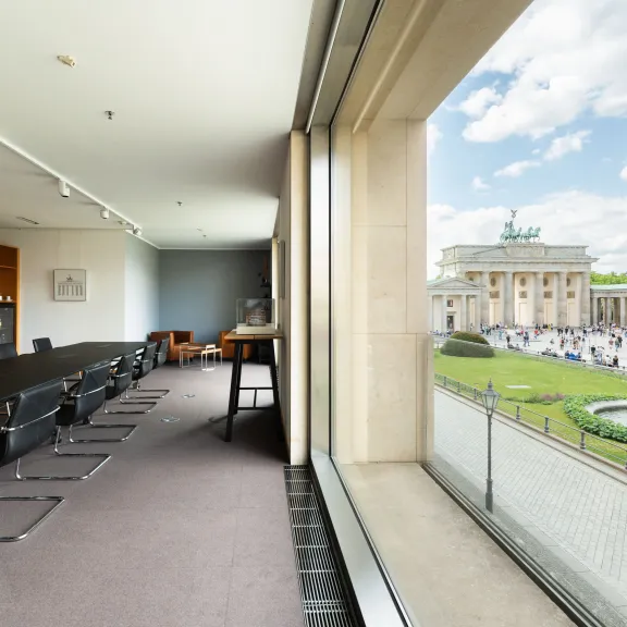 Konferenzraum mit Blick auf das Brandenburger Tor und einen Springbrunnen bei Tageslicht.