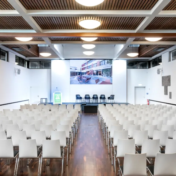 Leerer Konferenzraum mit weißen Stühlen und Podium vorne