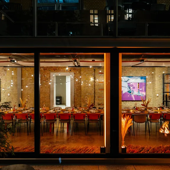 Modernes Restaurant mit langen, festlich gedeckten Tischen und warmem Licht.