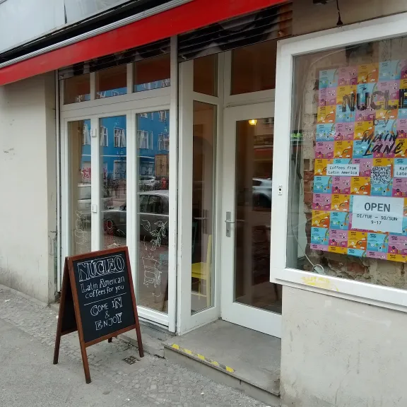 Café-Eingang mit bunter Fensterdekoration und Tafel vor der Tür.