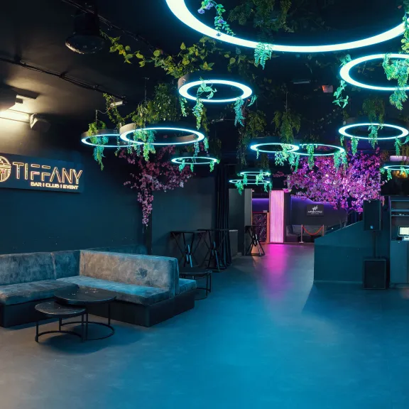 Modern eingerichtete Bar mit Neonlichtern, Pflanzen und gemütlichen Sitzbereichen.