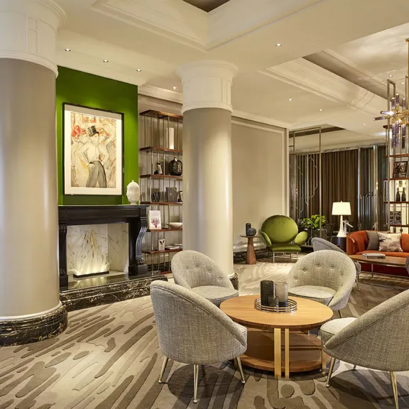 Modern eingerichtete Hotellobby mit Kamin, Sesseln, Sofas und großen Fenstern.