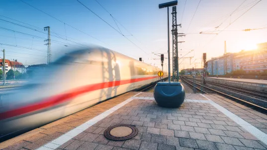 White high speed train in motion on the railway station at sunset. Germany. Blurred modern intercity train on the railway pl…