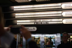 Menschen fotografieren die beleuchteten Deckenanzeigen im ICC, auf denen Veranstaltungsräume und Richtungen angezeigt werden