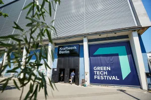 Eingang zum Green Tech Festival in Berlin mit Besuchern und großen blauen Bannern am Gebäude.