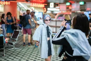 Besucher fotografieren sich in der futuristischen Eingangshalle des ICC Berlin mit Neonlichtern und Retro-Design.