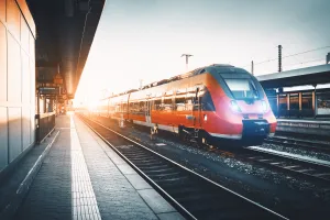 Moderner Regionalzug steht bei Sonnenuntergang an einem Bahnhofsgleis in Deutschland.