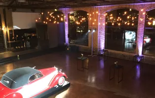 Roter Oldtimer in großer, elegant beleuchteter Eventhalle mit Lichterketten.