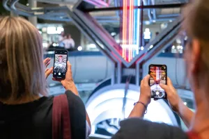 Zwei Personen fotografieren bunte Neonröhren mit ihren Smartphones im ICC Berlin.