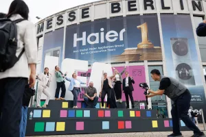 Menschen jubeln auf einer Bühne vor dem Eingang der Messe Berlin, Fotograf macht ein Bild.