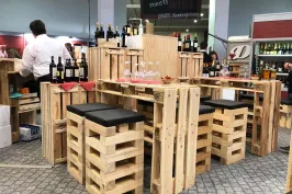 Holztische und Hocker aus Paletten mit Weinflaschen in einer modernen Bar.