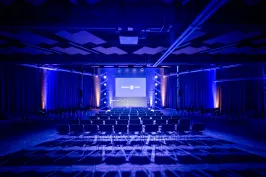 Leerer Konferenzsaal mit blauer Beleuchtung und Leinwand vorne
