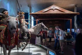 Ritterrüstungen auf Pferden in einem Museum, Besucher betrachten die Ausstellung.