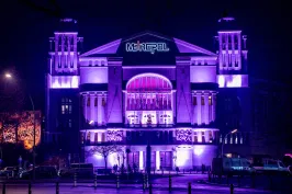 Beleuchtetes Theatergebäude bei Nacht in violetten und blauen Farbtönen