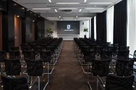 Leerer Konferenzraum mit Reihen schwarzer Stühle und Leinwand vorne