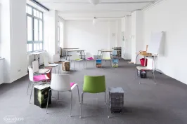 Raum mit grauem Teppich und bunten Stühlen