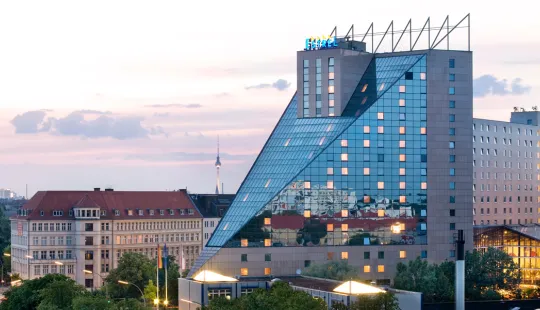 Modernes Hotelgebäude mit Glasfassade in einer Stadt bei Abenddämmerung.