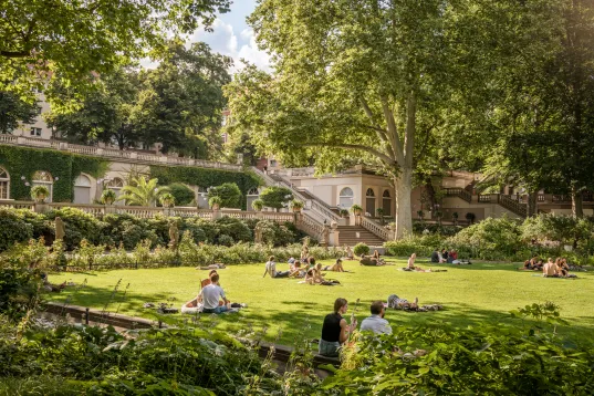 Der Körnerpark in Berlin Neukölln, Menschen sitzen im Gras und Picknicken
