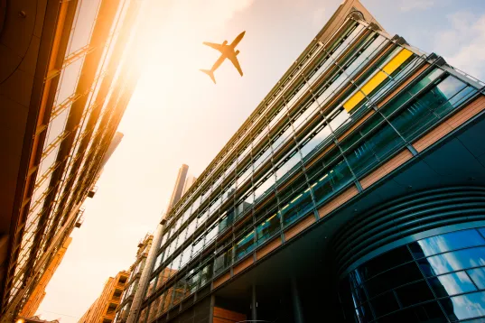 Flugzeug fliegt über Bürogebäude am Potsdamer Platz, von unten hoch fotografiert 