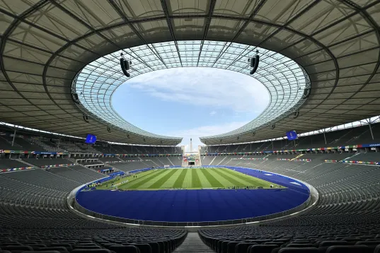 Leeres Fußballstadion mit offenem Dach und grünem Spielfeld