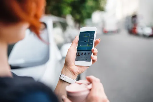 Frau bucht über eine App ein Carsharing Auto