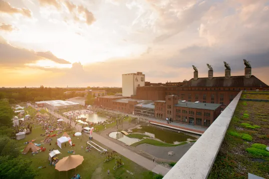 Die Malzfabrik ist aus der Ferne im warmen Licht des Sonnenuntergangs zu sehen.