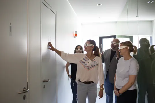 Menschen mit einer Brille ertasten an einer Wand etwas beim barrierefreien Markttag von Visit Berlin im Otto Bock Science Center